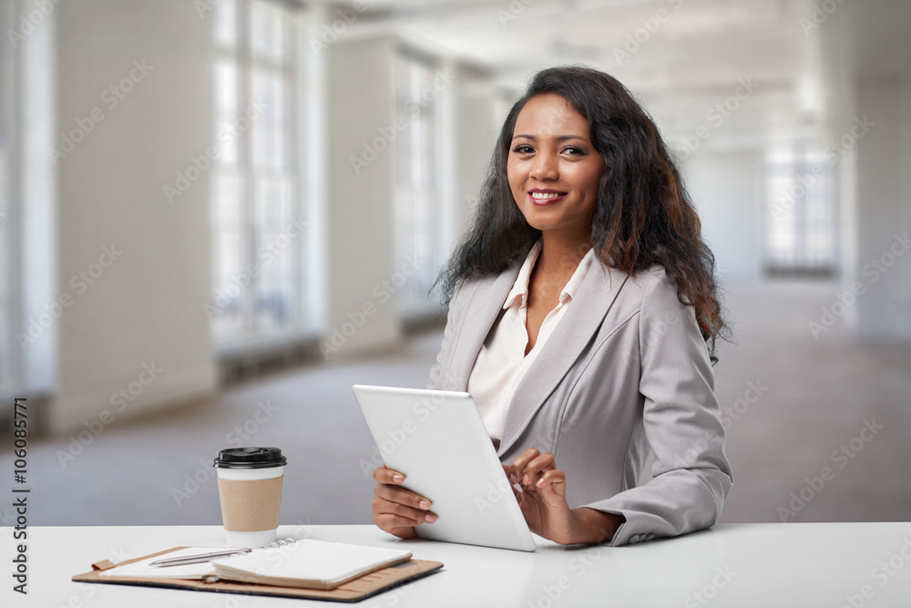 Pretty smiling business woman working on tablet computer at her desk