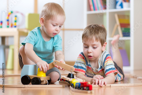 children playing rail road and car toys in playroom