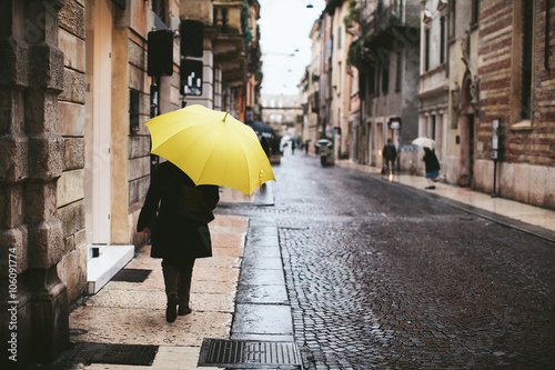 Fototapeta Naklejka Na Ścianę i Meble -  Woman with yellow umbrella is back on the streets of Verona