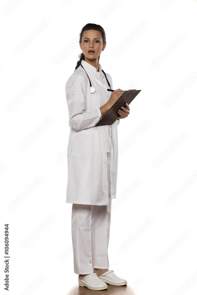 young woman doctor in uniform with clipboard on a white background young woman doctor in uniform with clipboard on a white background