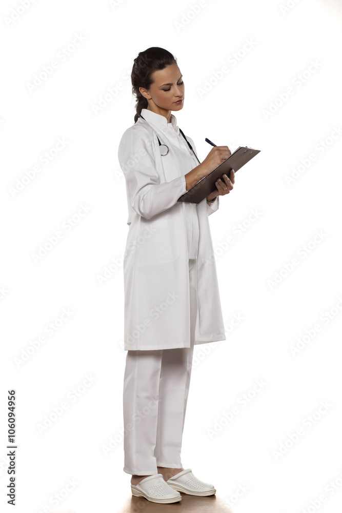 young woman doctor in uniform with clipboard on a white background young woman doctor in uniform with clipboard on a white background