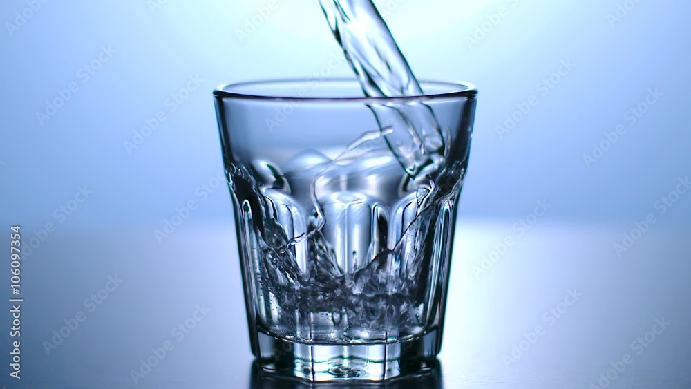 Wasser wird in Glas geschüttet, Zeitlupe, blauer Hintergrund
