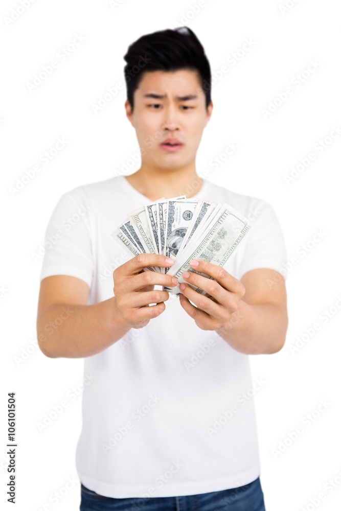 Upset young man counting fanned out currency notes Upset young man counting fanned out currency notes