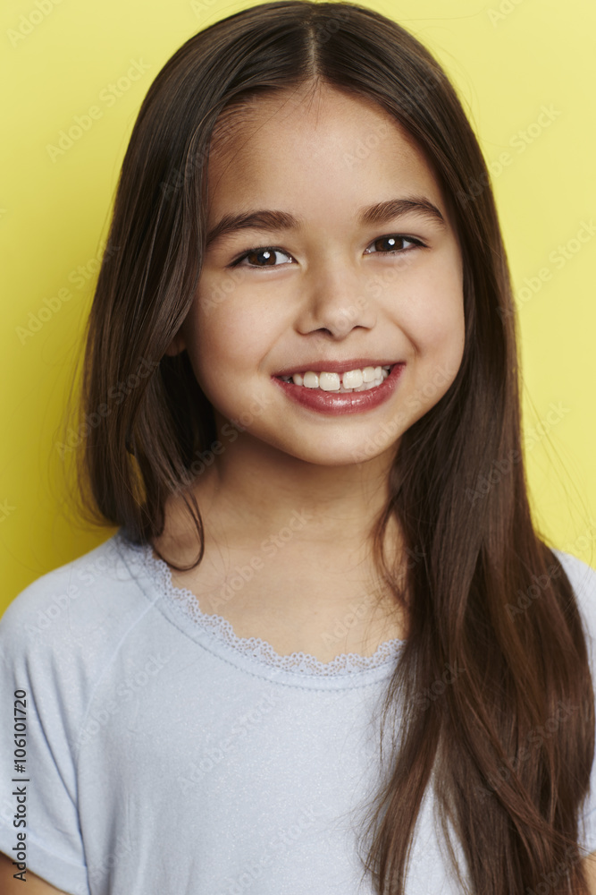Young girl smiling against yellow background Young girl smiling against yellow background