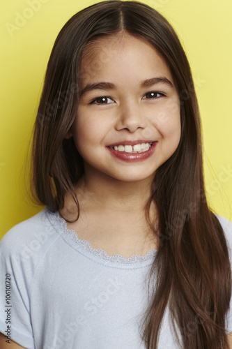 Young girl smiling against yellow background