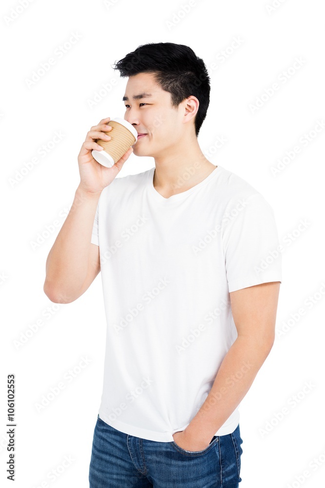 Young man drinking coffee from a disposable cup Young man drinking coffee from a disposable cup
