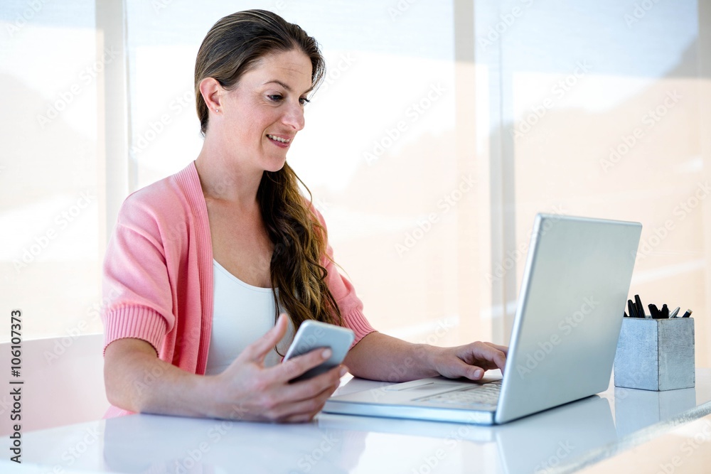 smiling woman on her laptop and smartphone smiling woman on her laptop and smartphone