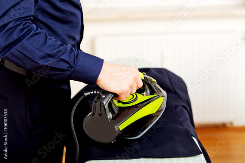 Young businessman ironing his jacket