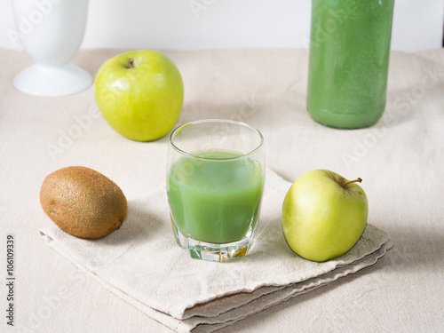 Glass of kiwi and green apple juice on beige napkin