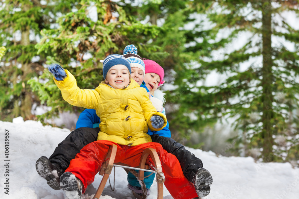 Children winter fun on sledge sliding down