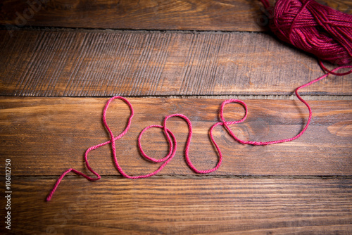 Inscription love from red wool thread on a wooden floor