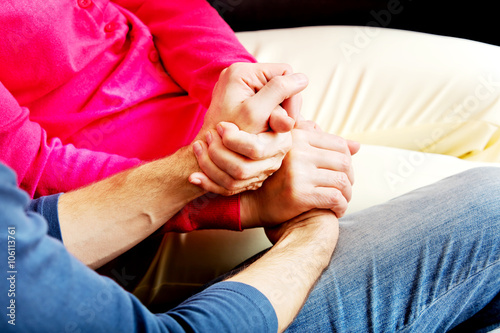 Mother and son sitting on couch and holding hands 