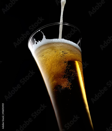glass of beer with foam on a black background