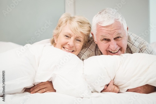 Happy senior couple resting on bed