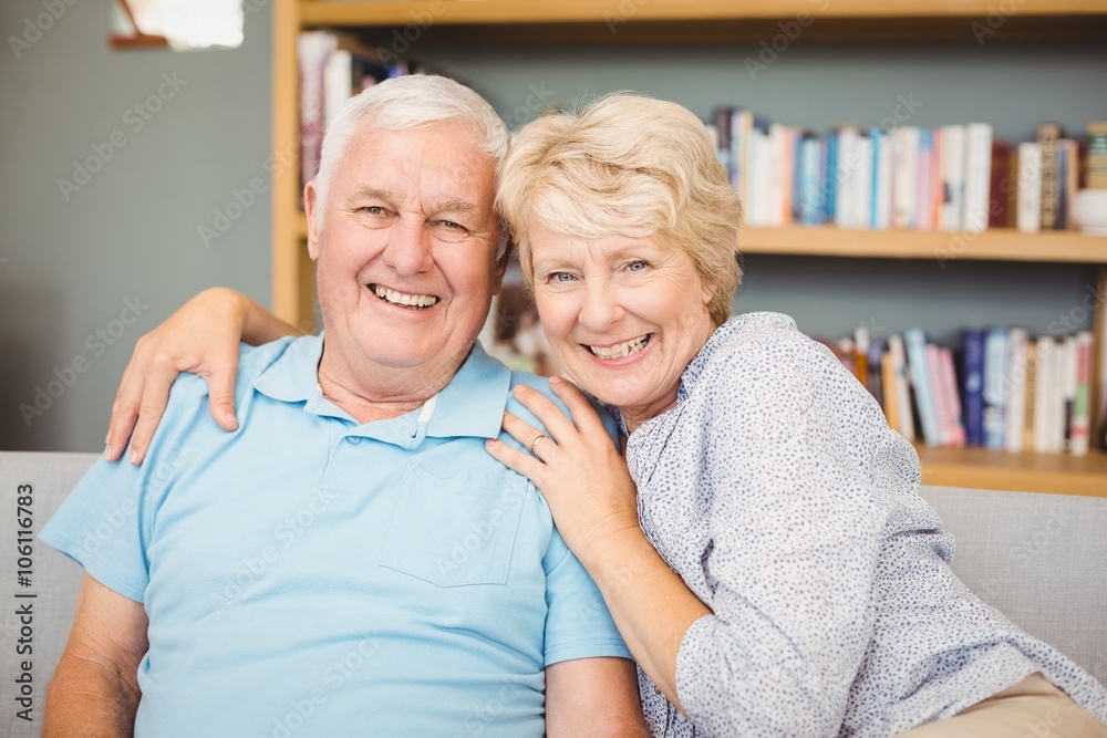 Senior couple sitting on sofa against bookshelf Senior couple sitting on sofa against bookshelf
