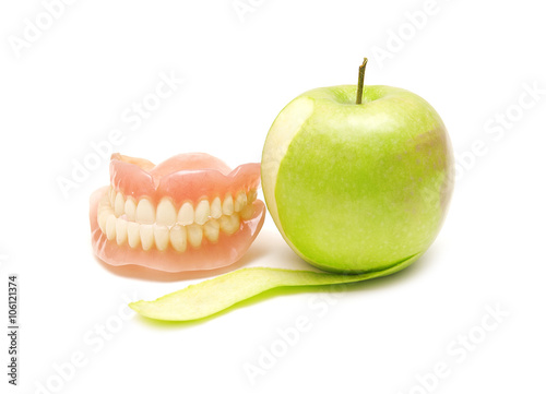 False teeth and green apple on a white background
