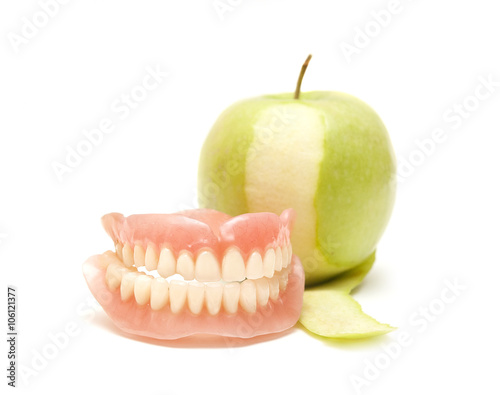 False teeth and green apple on a white background