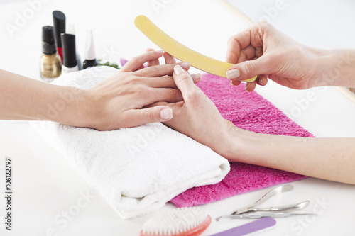 Woman in a nail salon receiving a manicure by a beautician.