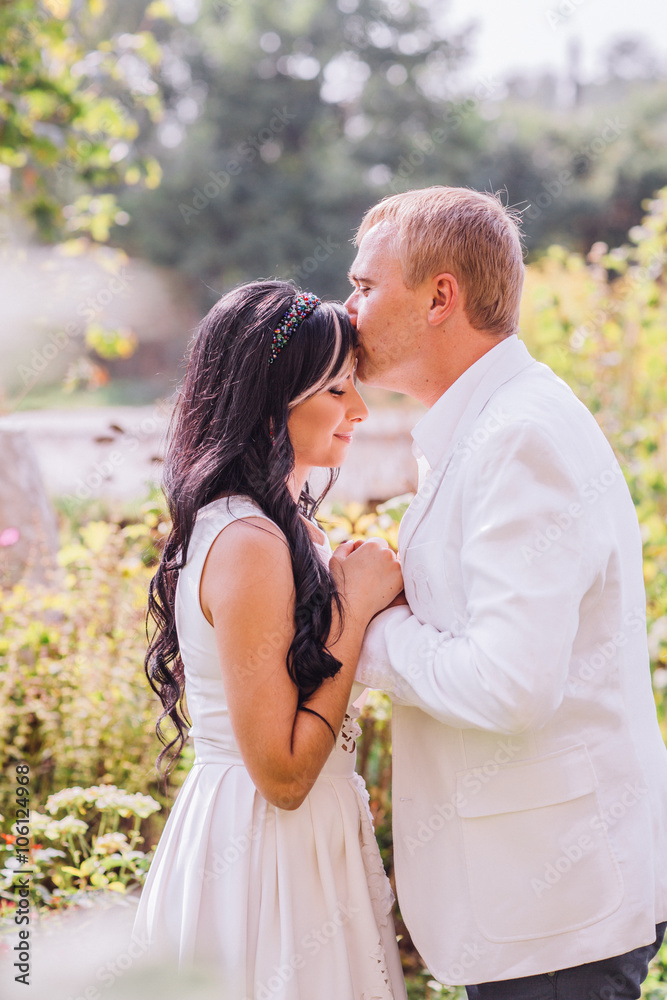 Handsome happy romantic groom and beautiful sensual bride in white dress posing under tent Handsome happy romantic groom and beautiful sensual bride in white dress posing under tent