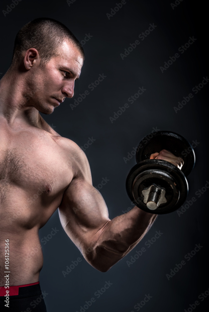 bodybuilder lifting dumbbells on dark background with copy space