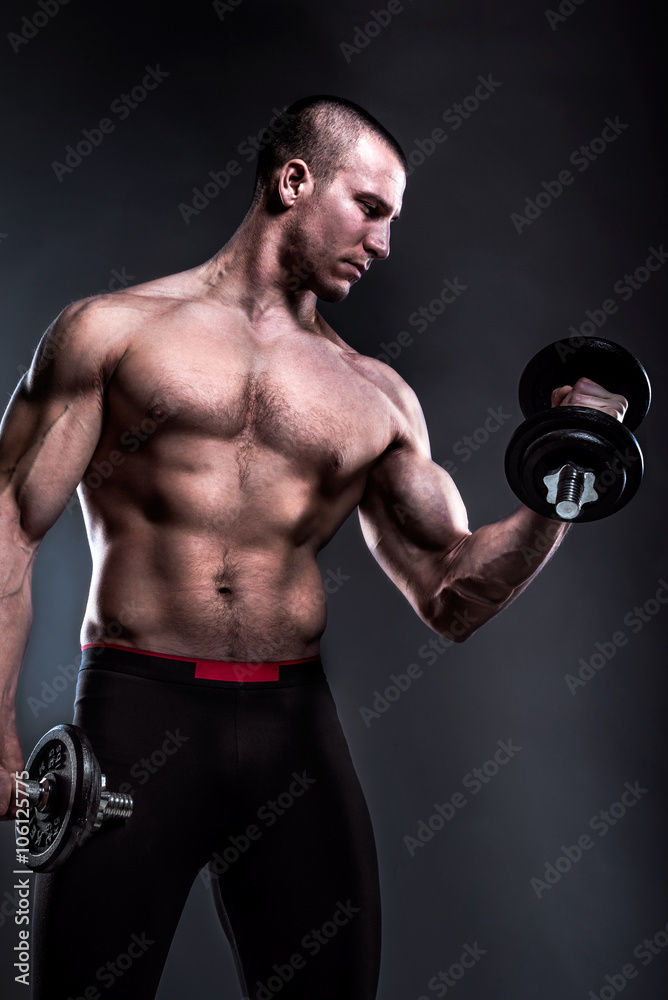 bodybuilder lifting dumbbells on dark background