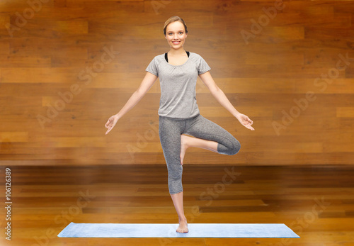 woman making yoga in tree pose on mat