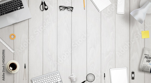 Work desk with free space for text surrounded with a lot of desk accessories. There is a laptop, tablet, phone, camera, headset, mouse, glasses, camera, pens, paper...