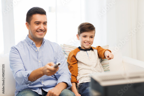 smiling father and son watching tv at home