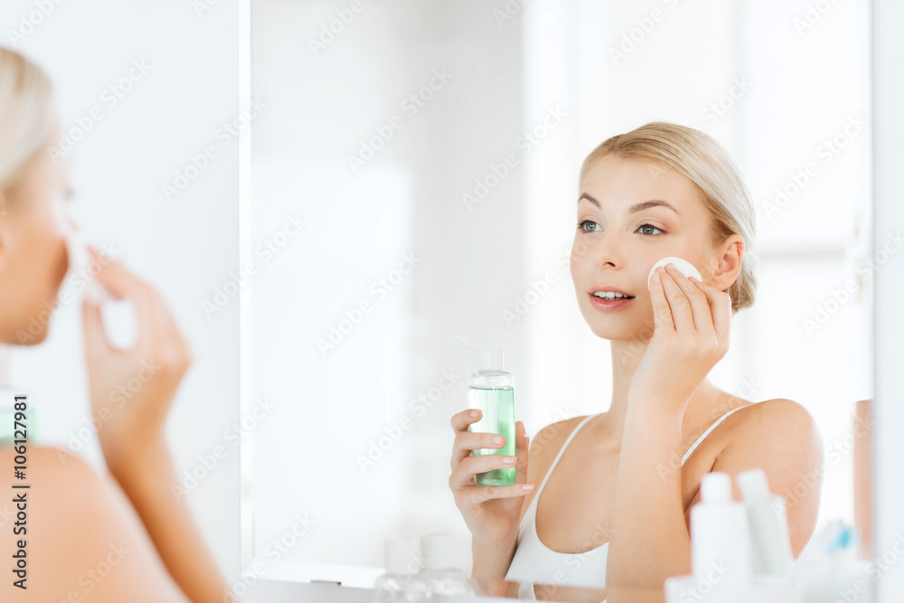 young woman with lotion washing face at bathroom young woman with lotion washing face at bathroom