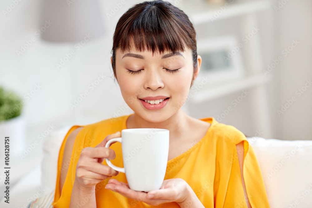 happy asian woman drinking from tea cup happy asian woman drinking from tea cup