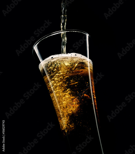 glass of beer with foam on a black background
