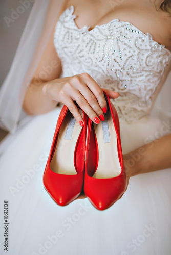 Photograph of a unrecognizable bride holding wedding red shoes