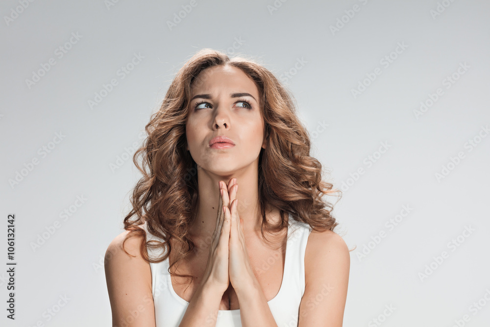 Woman is looking imploring over gray background Woman is looking imploring over gray background