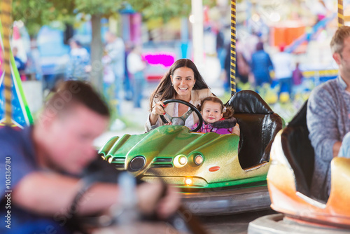 Mother and daughter in bumper car at fun fair © Halfpoint