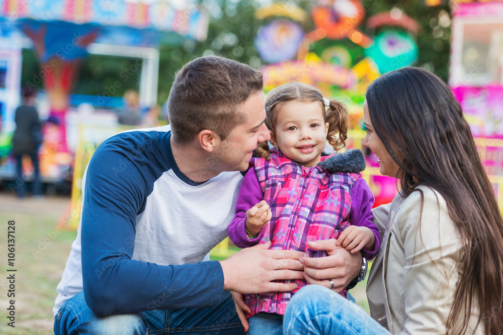 Obraz premium Father, mother and daughter having fun in amusement park