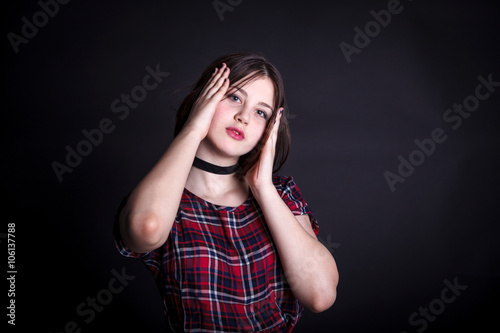 teen girl in a checkered dress posing on a dark background