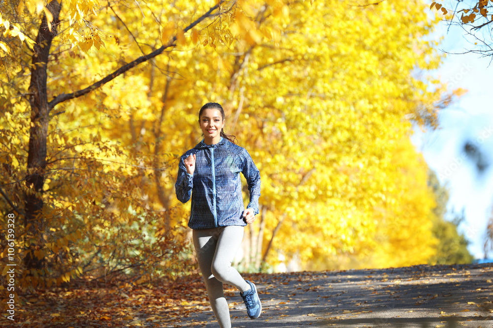 Fototapeta premium Young beautiful woman jogging in autumn park