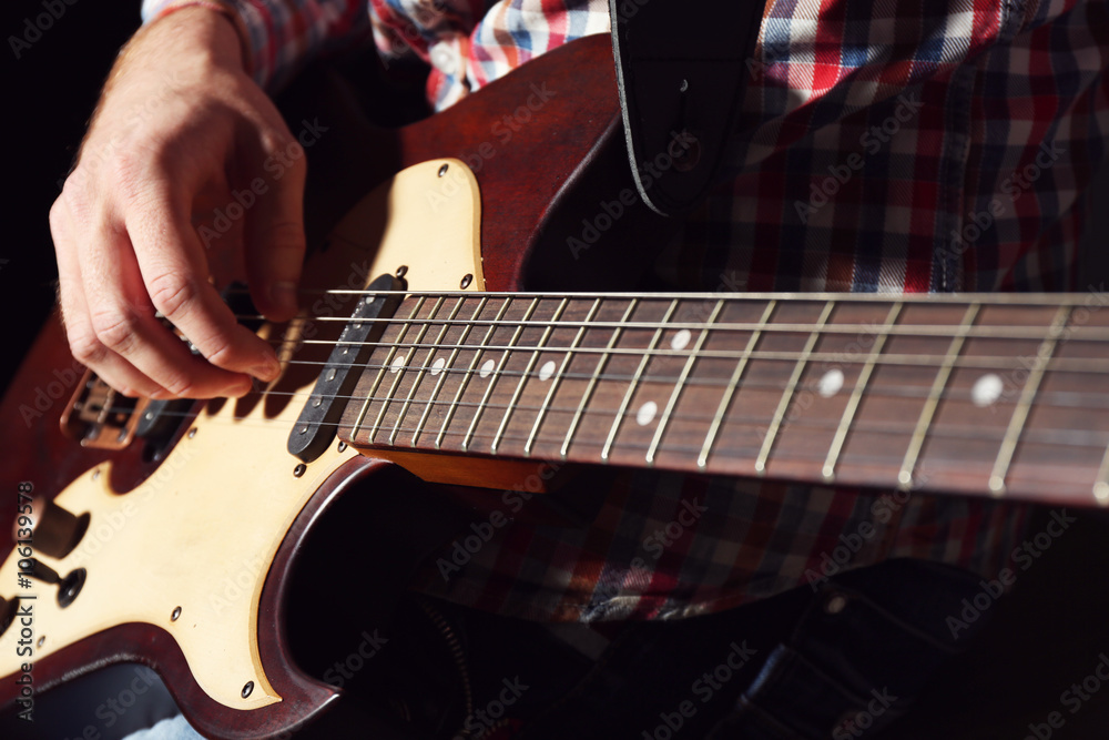 Fototapeta premium Young man playing on electric guitar close up
