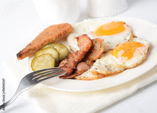 fried eggs with bacon and toasts on white background 