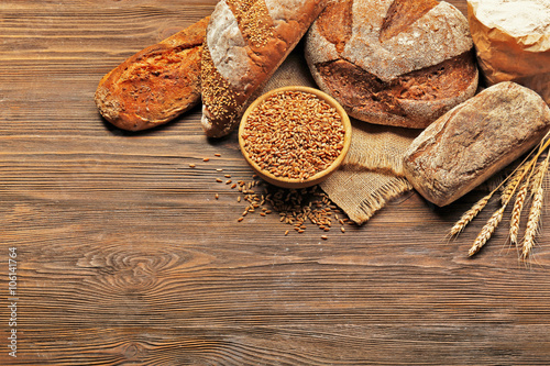 Fresh baked bread and a bowl of wheat grains on the wooden background