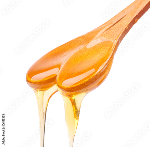 Honey dripping from a wooden spoon isolated