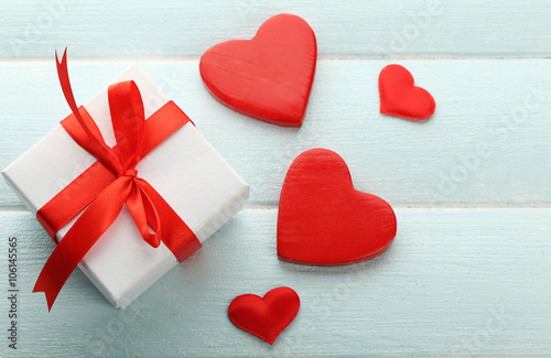 Gift box and decorative hearts on color wooden background © Africa Studio