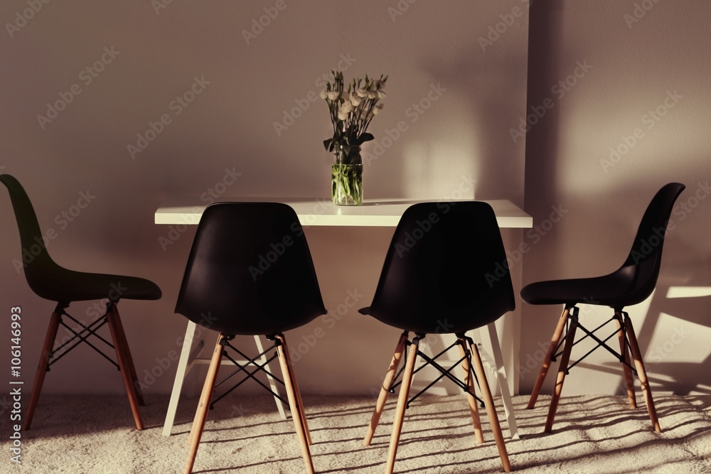 Modern dining room. White table with bouquet of flowers and black chairs Modern dining room. White table with bouquet of flowers and black chairs