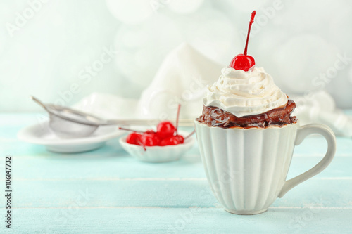 Chocolate mug cake with cream and cherry on a table photo