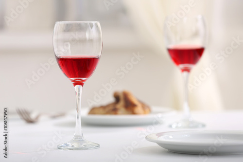 Dinner with glasses of wine at table on light blurred background