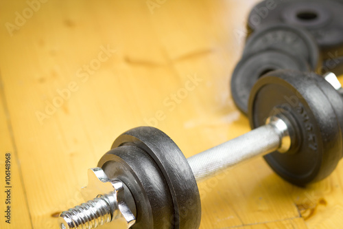 Big black dumbells on wood floor in the huge gym / fitness; spor