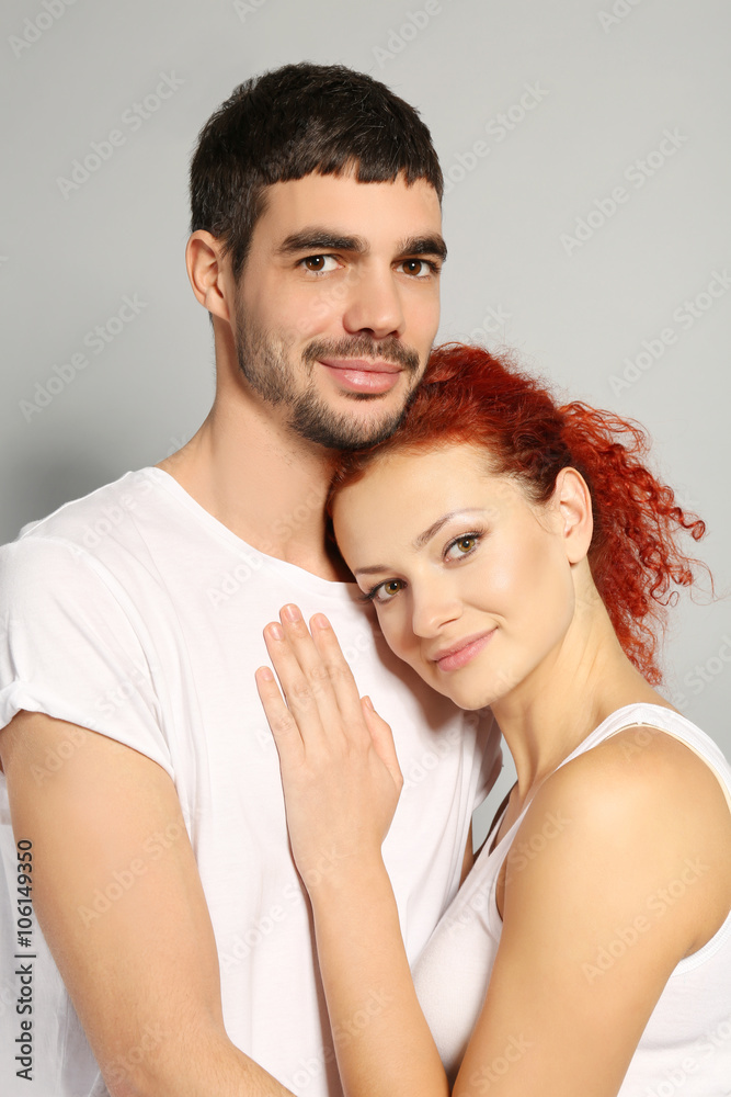 Happy young couple in love embracing on grey background, close up Happy young couple in love embracing on grey background, close up