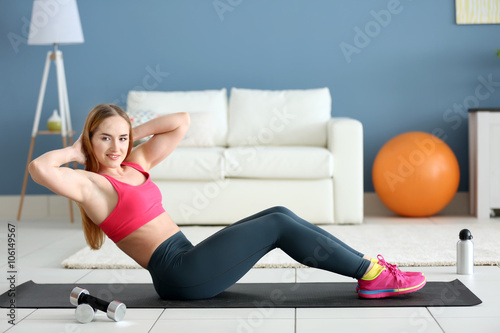 Young sportswoman doing exercises on a mat at home