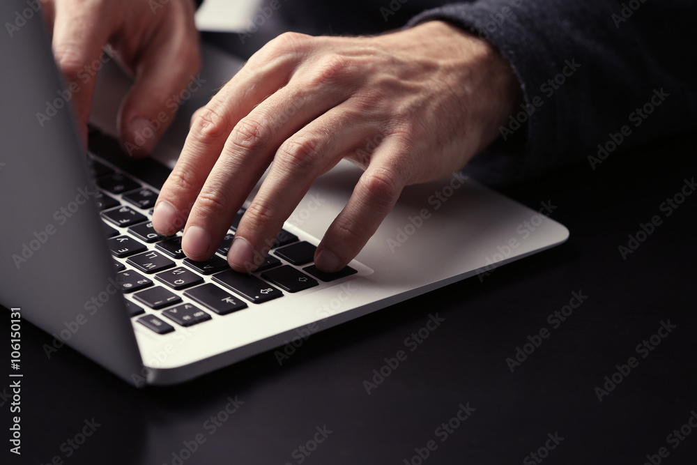 Male hands typing on laptop keyboard at table closeup Male hands typing on laptop keyboard at table closeup