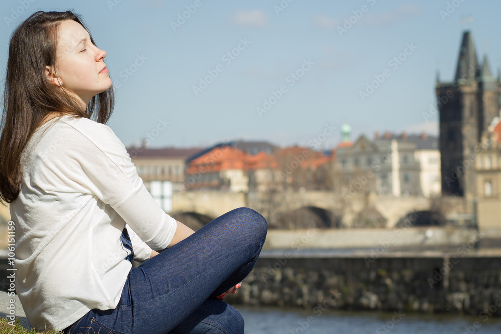 Pretty young girl relaxing near by river and watching out to the